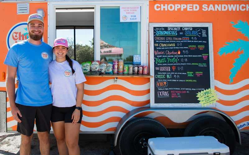 Couple standing in front of chopped sandwich truck