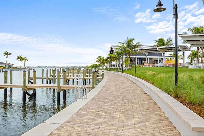 Scenic waterfront path with palm trees and docks.