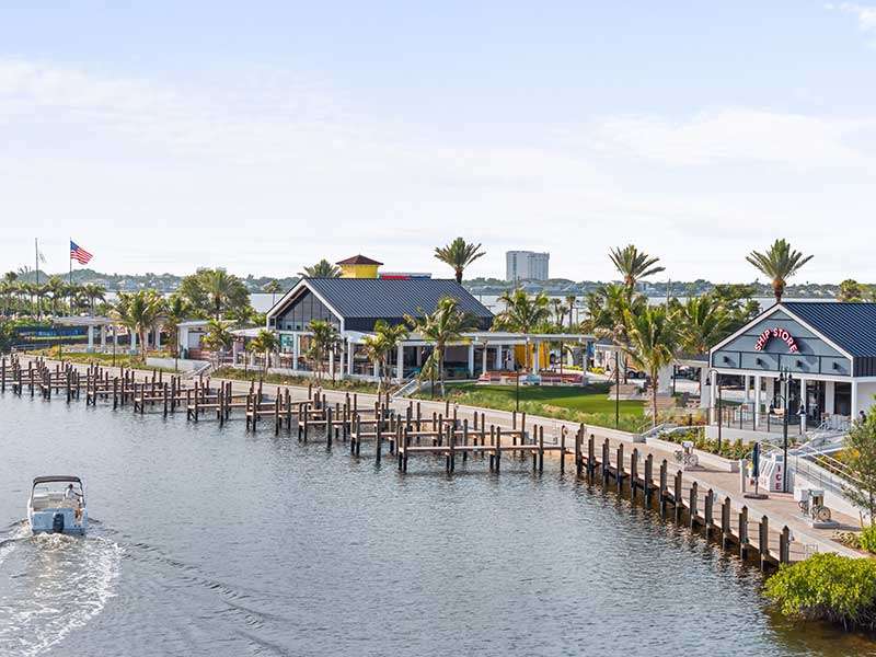 Scenic waterfront with shops and palm trees.